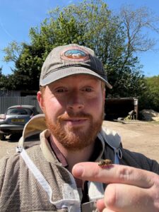 MD Falconry pest control specialist outdoors holding a bee